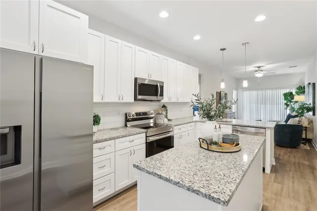 a kitchen with a refrigerator a stove a sink dishwasher with a dining table and chairs with wooden floor