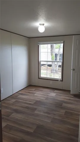 an empty room with wooden floor and windows with curtains