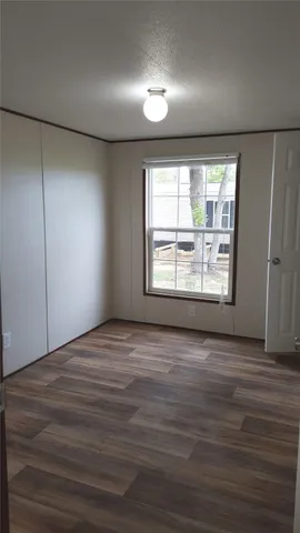 an empty room with wooden floor and windows with curtains