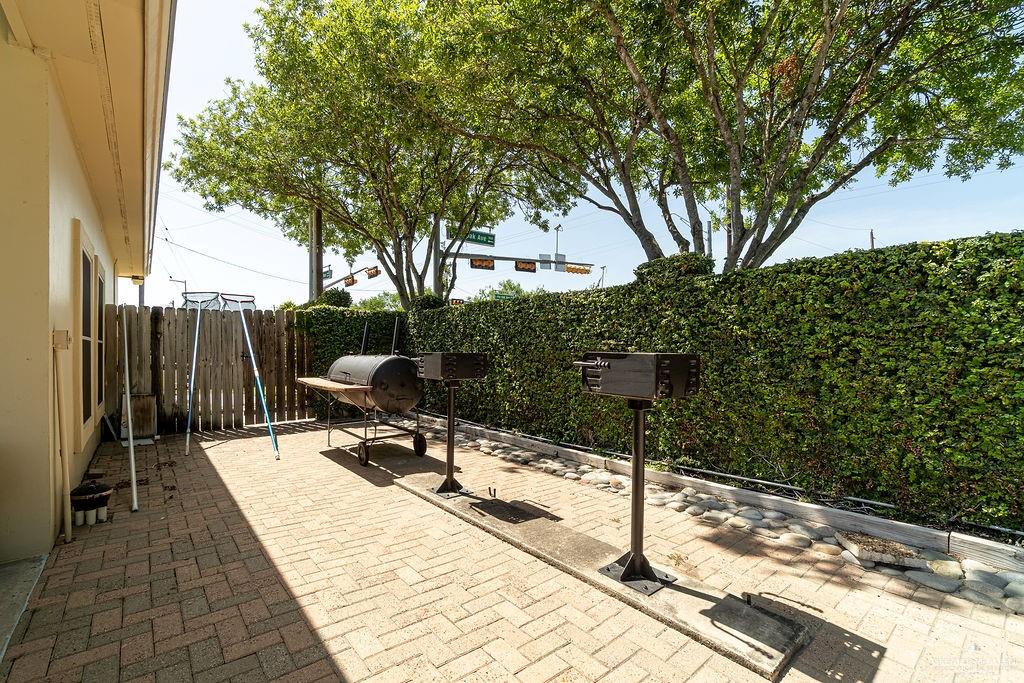 919 Hill Country Road Edinburg, TX 78539 - Photo 19 of 22 Patio area featuring brick paver flooring, a perimeter hedge, and a wooden fence