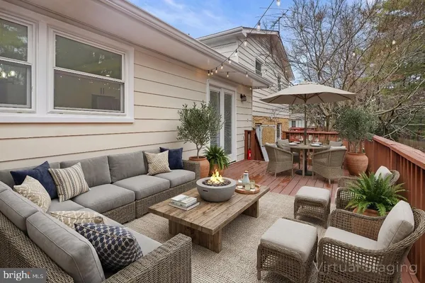 a view of a patio with couches table and chairs under an umbrella with a barbeque