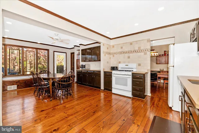 a kitchen with stainless steel appliances kitchen island granite countertop a stove top oven a dining table and chairs with wooden floor