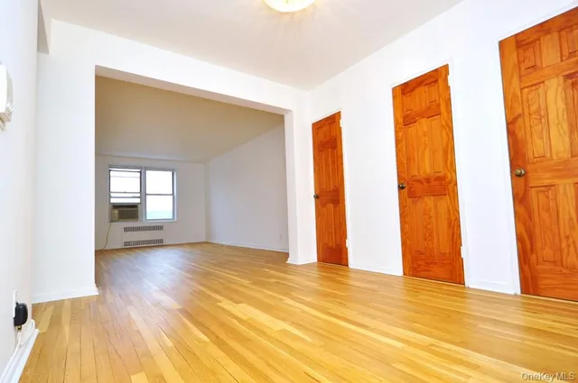 a view of an empty room with window and wooden floor