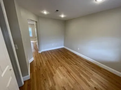 an empty room with wooden floor and entrance