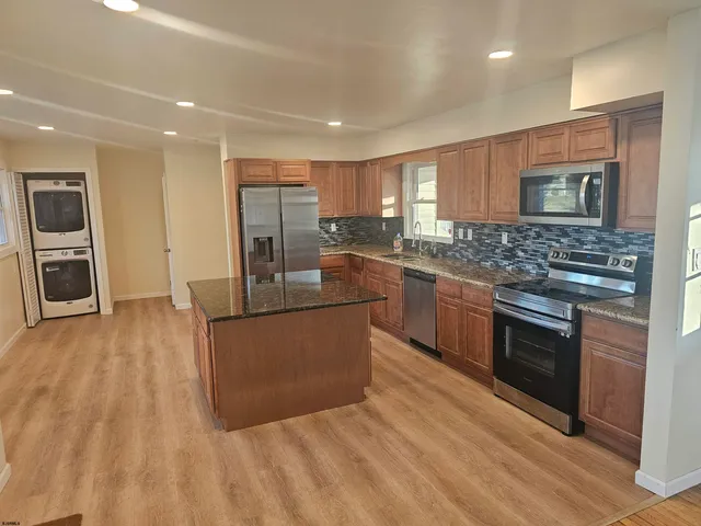 a kitchen with stainless steel appliances granite countertop a stove top oven a sink dishwasher a refrigerator and a oven with wooden floor