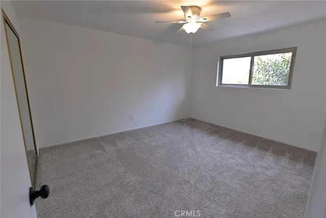 an empty room with windows and fan