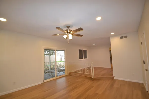 a view of an empty room with wooden floor and a window
