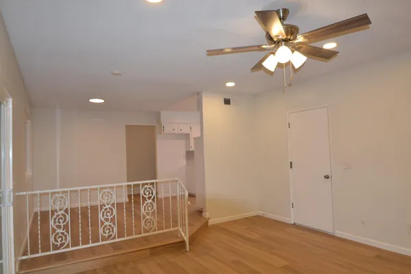 an empty room with wooden floor fan and windows