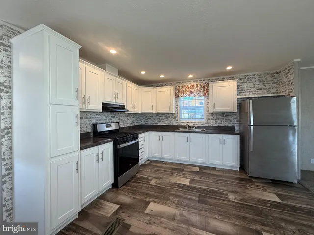 a large kitchen with granite countertop a refrigerator stove top oven and cabinets
