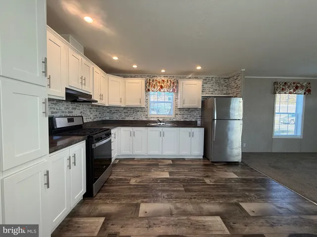 a large kitchen with stainless steel appliances granite countertop a stove a refrigerator a sink and dishwasher