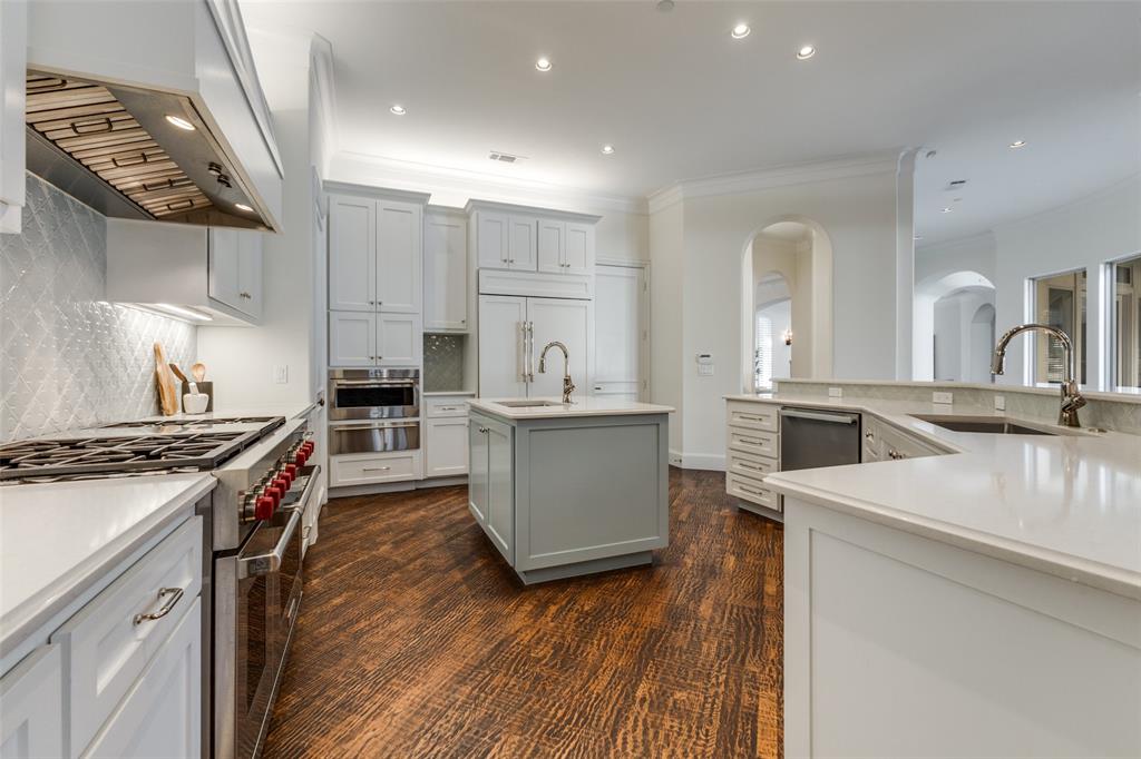 14828 Bellbrook Drive Addison, TX 75254 - Photo 16 of 36 a kitchen with stainless steel appliances granite countertop a stove top oven a sink and white cabinets with wooden floor
