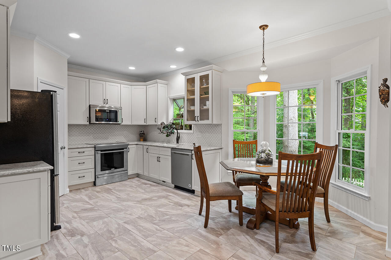 2604 Clerestory Place Raleigh, NC 27615 - Photo 19 of 37 a kitchen with a table chairs refrigerator and microwave