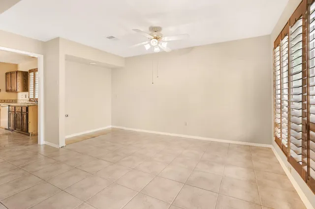 an empty room with windows and chandelier fan