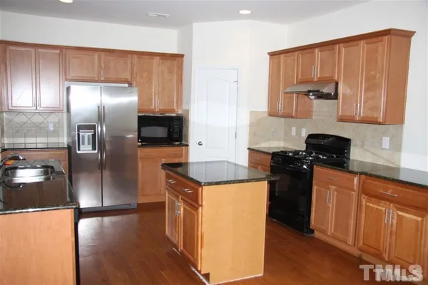a kitchen with stainless steel appliances granite countertop a refrigerator a stove and a sink with wooden floor