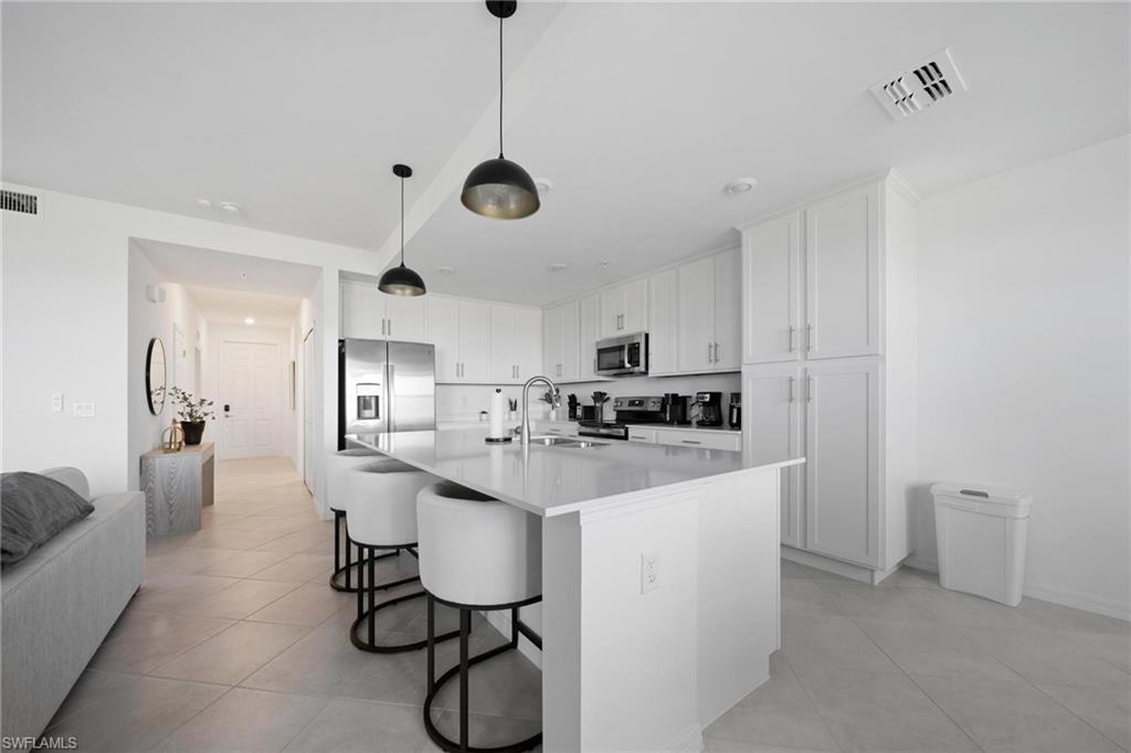 43997 Boardwalk Loop, Unit 1837 Babcock Ranch, FL 33982 - Photo 11 of 26 a kitchen with stainless steel appliances a sink a stove a refrigerator cabinets and chairs