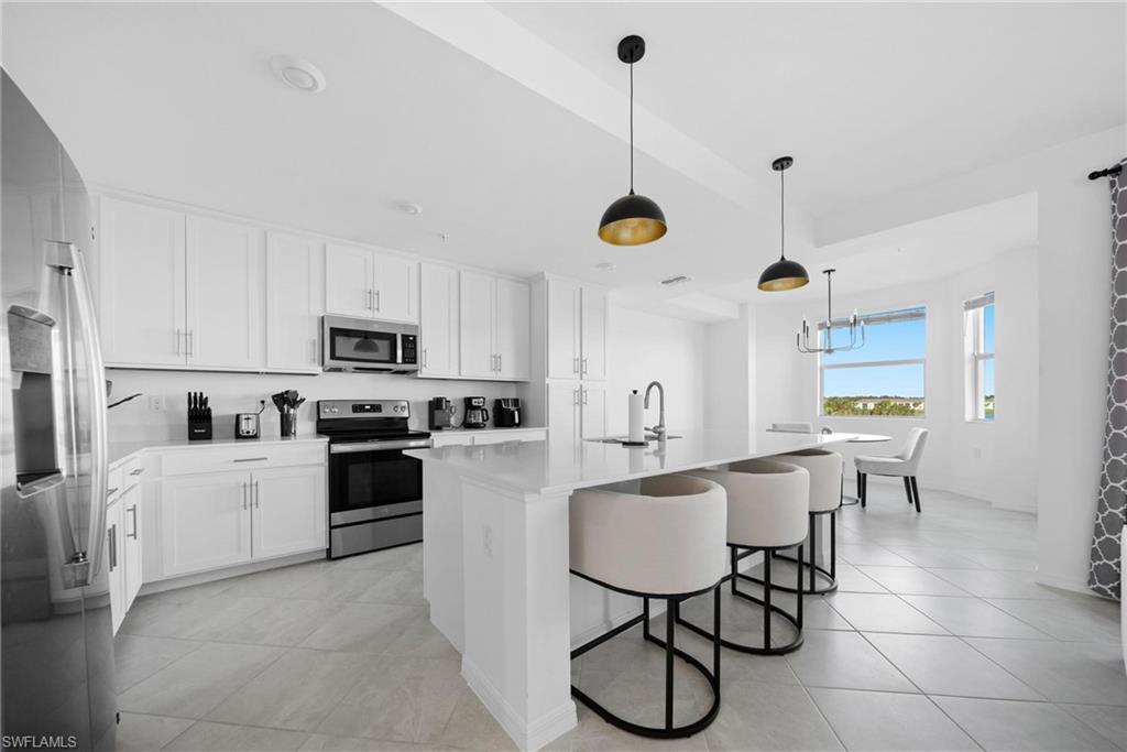 43997 Boardwalk Loop, Unit 1837 Babcock Ranch, FL 33982 - Photo 3 of 26 a kitchen with stainless steel appliances granite countertop a sink a stove a refrigerator and microwave