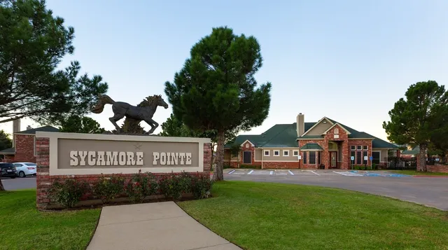 a view of a park that has a sign board large trees