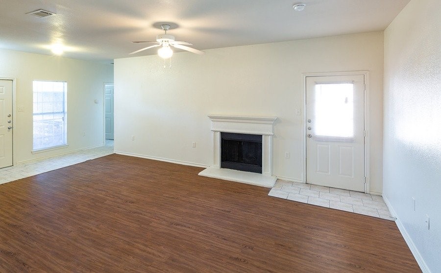 2201 Sycamore School Road Fort Worth, TX 76134 - Photo 9 of 12 an empty room with wooden floor a chandelier fan and windows