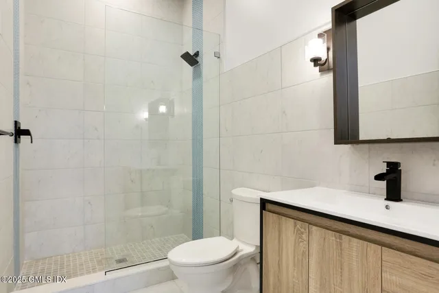 a bathroom with a sink a toilet a mirror and shower