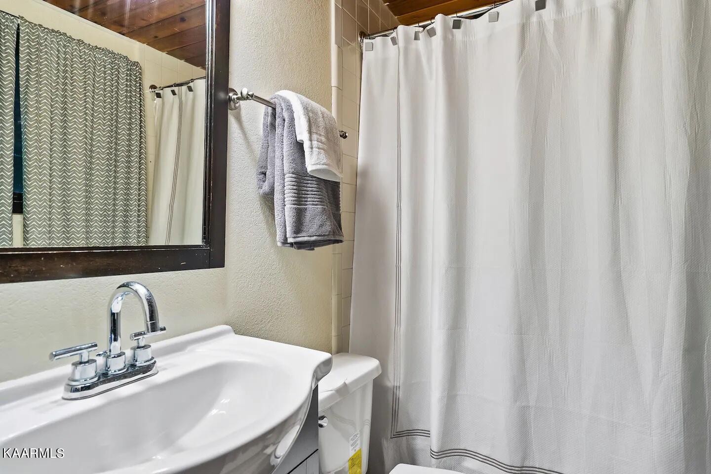 1424 Zurich Road Gatlinburg, TN 37738 - Photo 23 of 27 a bathroom with a sink a mirror and a shower curtain
