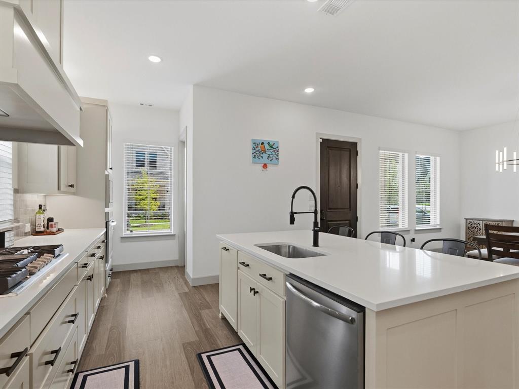 9533 Keep Street Frisco, TX 75035 - Photo 11 of 40 Modern kitchen featuring light-toned cabinetry, stainless steel appliances, and a central island with a sink and seating area