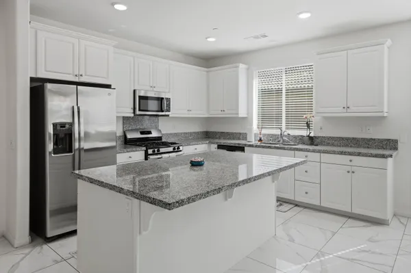 a kitchen with granite countertop a refrigerator sink and cabinets