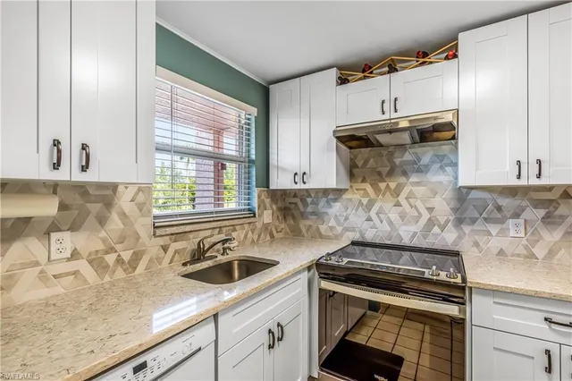 a kitchen with granite countertop a sink stove and cabinets