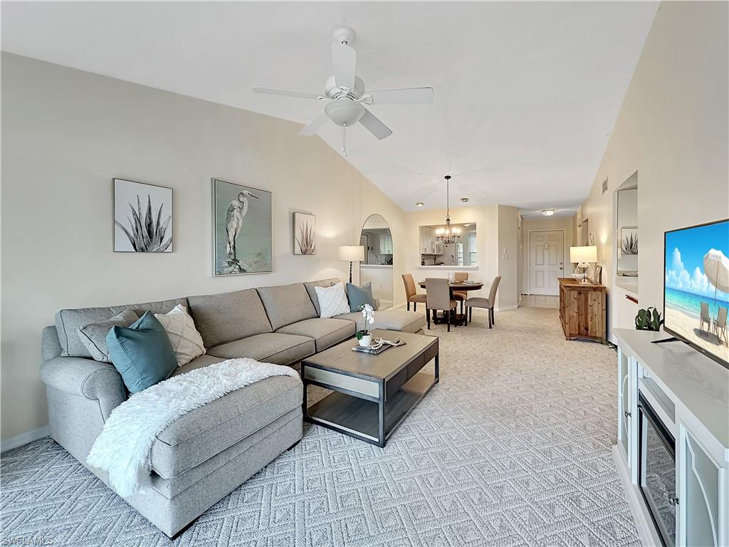 905 Augusta Boulevard, Unit 9056 Naples, FL 34113 - Photo 14 of 28 Carpeted living room with lofted ceiling and ceiling fan with notable chandelier
