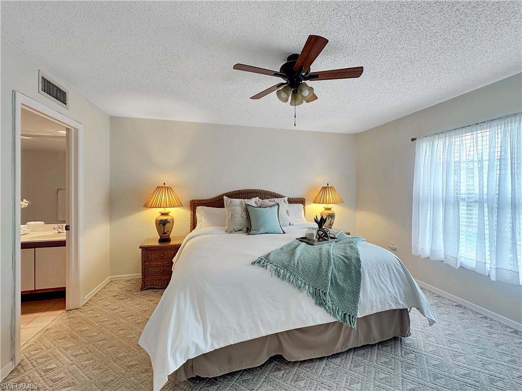 905 Augusta Boulevard, Unit 9056 Naples, FL 34113 - Photo 17 of 28 Bedroom featuring light carpet, multiple windows, a textured ceiling, and ceiling fan