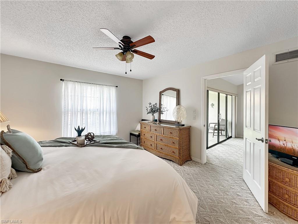 905 Augusta Boulevard, Unit 9056 Naples, FL 34113 - Photo 19 of 28 Bedroom with ceiling fan, light carpet, and a textured ceiling