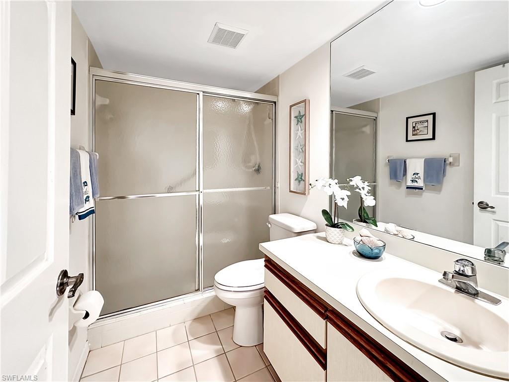 905 Augusta Boulevard, Unit 9056 Naples, FL 34113 - Photo 24 of 28 Bathroom with tile patterned floors, toilet, a shower with door, and vanity