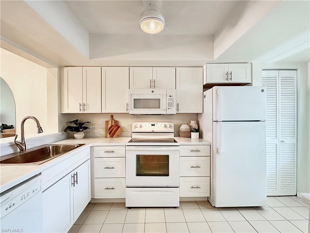 905 Augusta Boulevard, Unit 9056 Naples, FL 34113 - Photo 4 of 28 Kitchen with light tile patterned flooring, white appliances, white cabinetry, and sink
