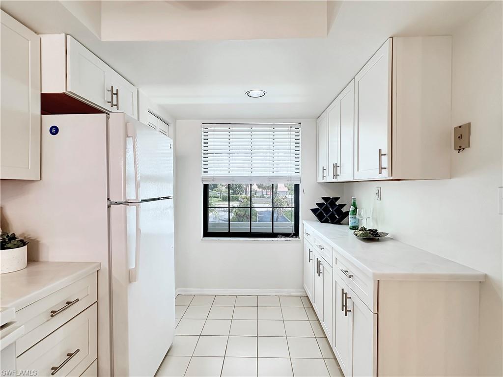 905 Augusta Boulevard, Unit 9056 Naples, FL 34113 - Photo 5 of 28 Kitchen featuring white refrigerator, light tile patterned floors, and white cabinetry