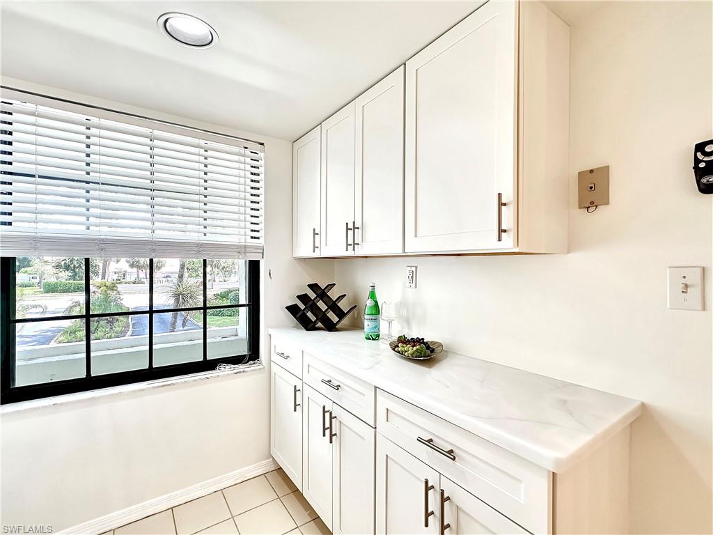 905 Augusta Boulevard, Unit 9056 Naples, FL 34113 - Photo 6 of 28 Kitchen featuring white cabinetry, light stone counters, and light tile patterned floors