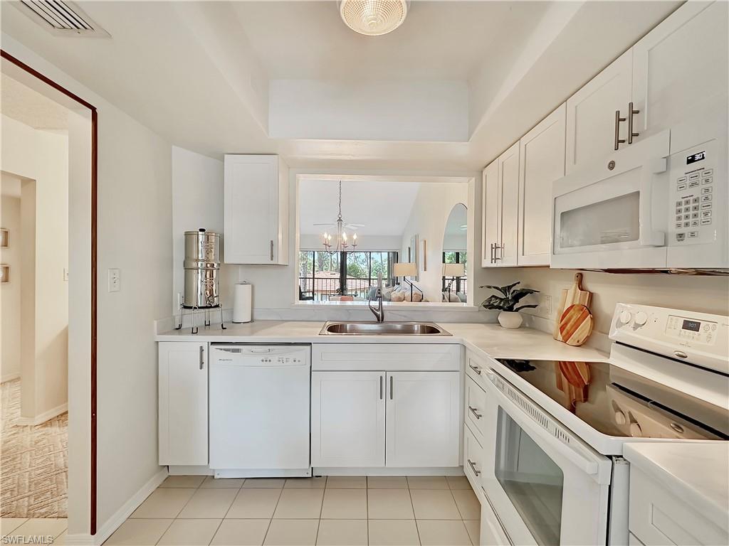 905 Augusta Boulevard, Unit 9056 Naples, FL 34113 - Photo 7 of 28 Kitchen featuring white appliances, a chandelier, light tile patterned floors, sink, and white cabinets