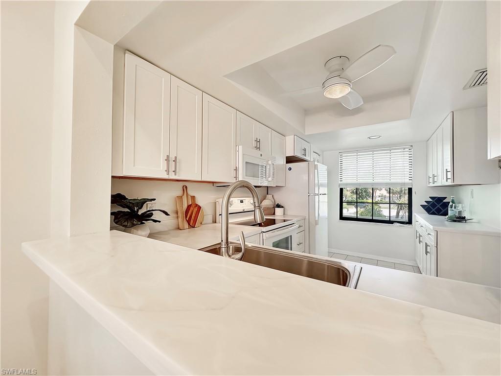 905 Augusta Boulevard, Unit 9056 Naples, FL 34113 - Photo 8 of 28 Kitchen featuring white appliances, white cabinetry, sink, a tray ceiling, and ceiling fan