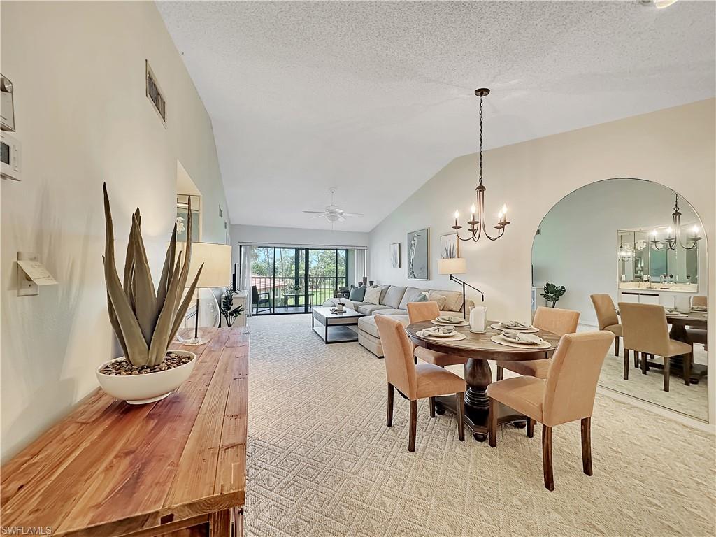 905 Augusta Boulevard, Unit 9056 Naples, FL 34113 - Photo 9 of 28 Carpeted dining space featuring ceiling fan with notable chandelier, lofted ceiling, and a textured ceiling
