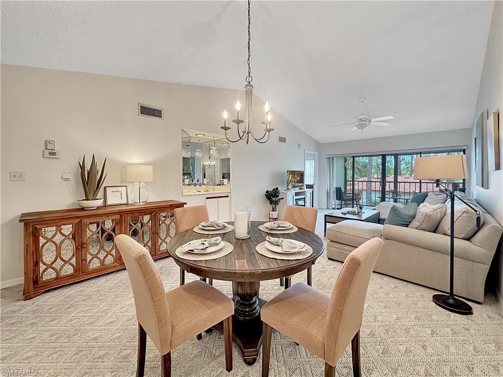 905 Augusta Boulevard, Unit 9056 Naples, FL 34113 - Photo 10 of 28 Dining room featuring ceiling fan with notable chandelier, lofted ceiling, and light colored carpet