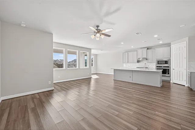 a view of an empty room with window and wooden floor