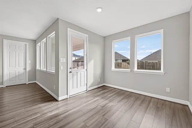 a view of an empty room with wooden floor and a window