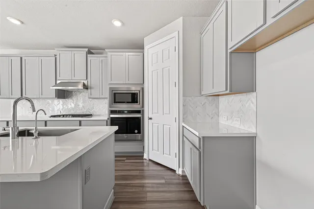 a kitchen with kitchen island granite countertop a sink stove and refrigerator