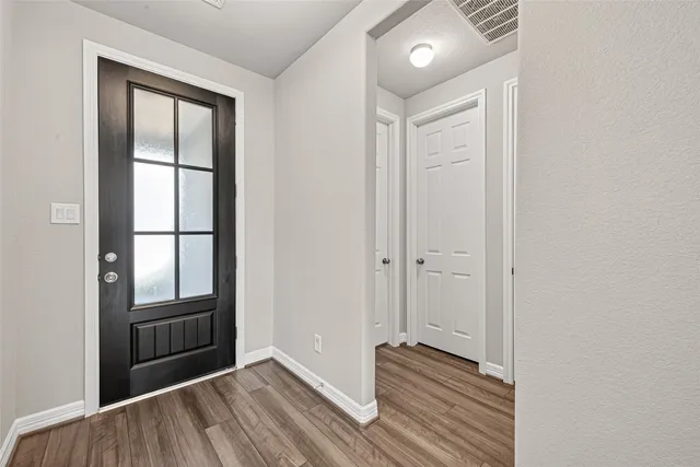 an empty room with wooden floor cabinet and front door
