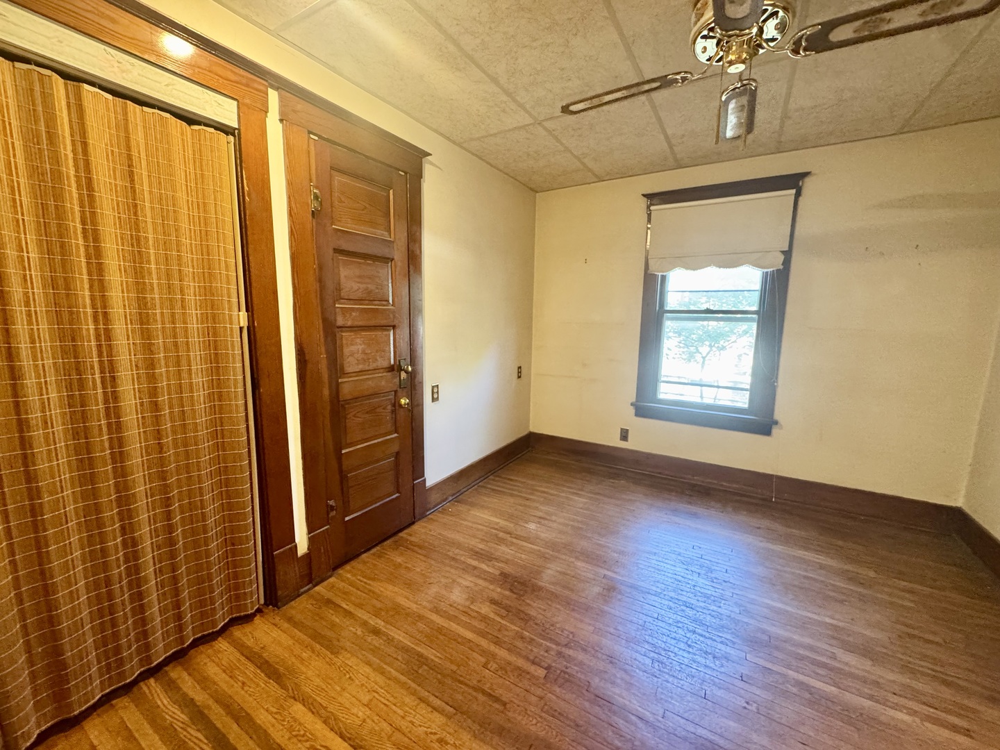 303 South Elm Street Clinton, IL 61727 - Photo 10 of 17 an empty room with wooden floor and windows with curtains