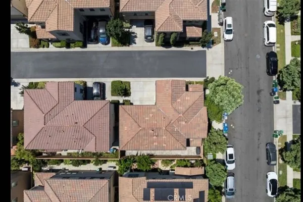 an aerial view of a house with a yard and a large building in the background