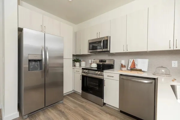 a kitchen with stainless steel appliances granite countertop a refrigerator a stove a sink and white cabinets