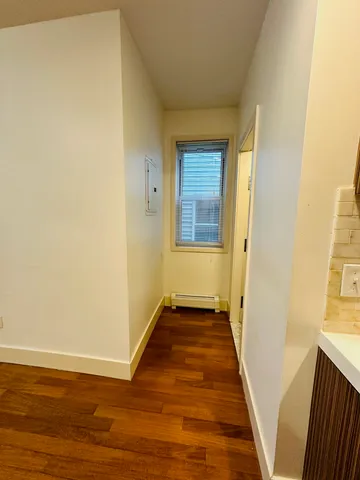 a view of an empty room with wooden floor and a window