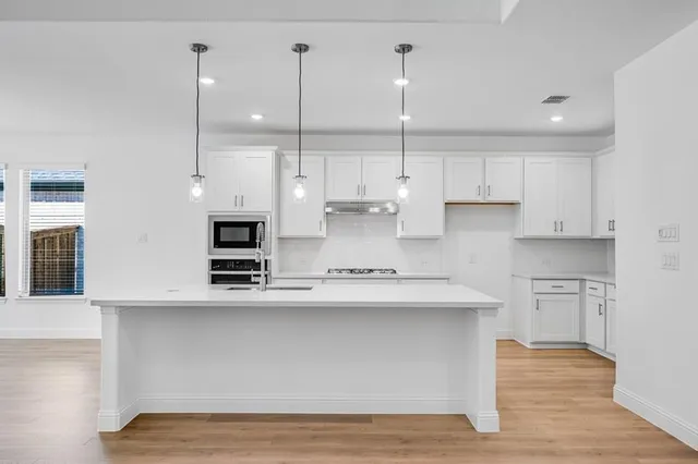 a kitchen with stainless steel appliances granite countertop a sink a oven and a white cabinets