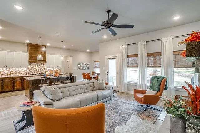 a living room with furniture kitchen view and a large window