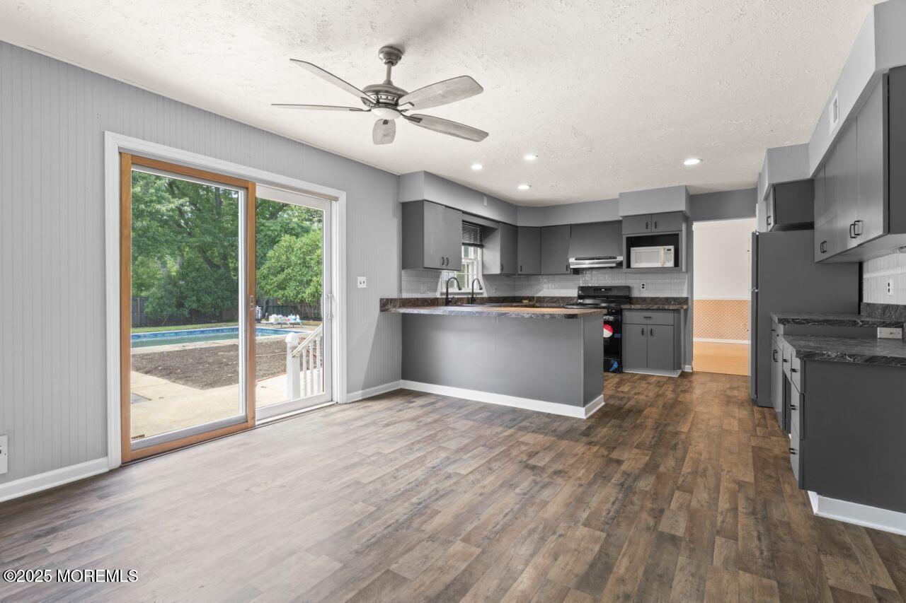 600 Driscol Drive Brick, NJ 08724 - Photo 7 of 35 a kitchen with stainless steel appliances granite countertop a refrigerator a stove top oven a sink with wooden floors and cabinets
