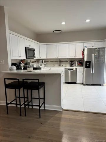 a kitchen with stainless steel appliances granite countertop a table chairs sink and cabinets